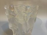 a glass vase with a statue on it on a table
