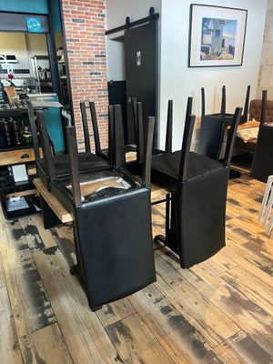tables and chairs in a room with a brick wall and wood floor