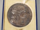 a silver coin with a woman ' s head and a crown on it