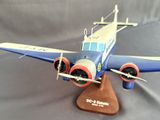 a small model of a blue and white airplane on a wooden stand