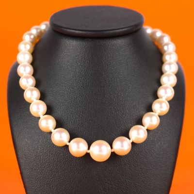 a close up of a necklace with pearls on a mannequin
