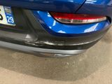 the rear end of a blue car with a number plate on it