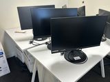 trois écrans d'ordinateur posés sur un bureau dans un bureau