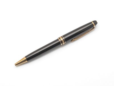un stylo noir et or posé sur une surface blanche