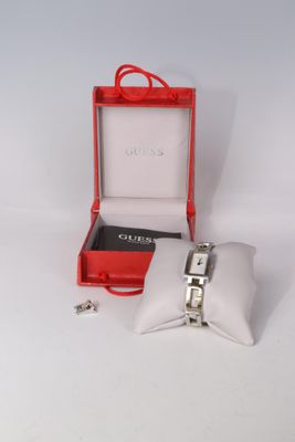 une boîte rouge contenant une montre argentée et un oreiller blanc