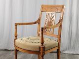 une chaise en bois avec une assise beige et un rideau blanc en arrière-plan