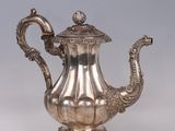 an antique silver tea pot with a handle on a white surface