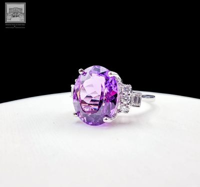 an oval cut amethorate and diamond ring on a white surface