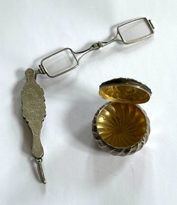 une cuillère en argent et une paire de verres posés sur une table blanche