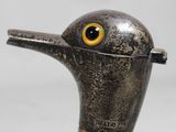 a close up of a metal duck with a yellow eye