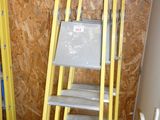 yellow ladders are lined up against a wall in a room