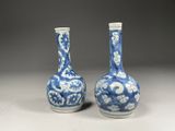 une paire de vases bleus et blancs posés sur une table, sur fond gris