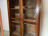 une vieille armoire en bois avec des portes vitrées et des étagères, dans une pièce