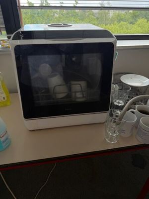 a microwave sitting on a table with a cup of coffee