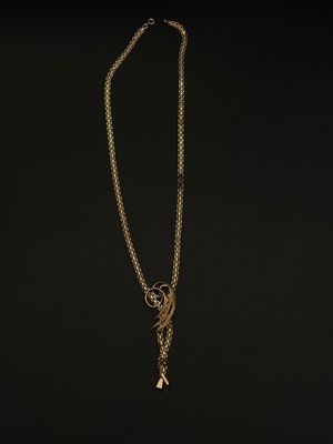 un collier en or auquel est suspendue une breloque en forme d'oiseau
