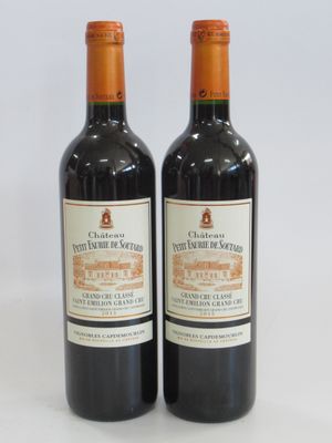 two bottles of red wine sitting next to each other on a white surface