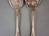 une paire de cuillères en argent ornées de motifs floraux, posées sur une table