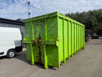 une benne verte garée sur un parking à côté d'une camionnette blanche