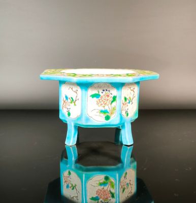 a small blue table with flowers on it on a black surface