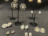 a group of silver and gold earrings and brooches on stands