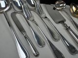 a lot of silver spoons and knives on the table
