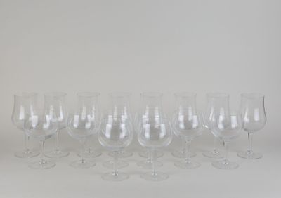 twelve empty wine glasses lined up in a row against a white background