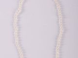 un collier de perles blanches avec un fermoir en or sur fond blanc
