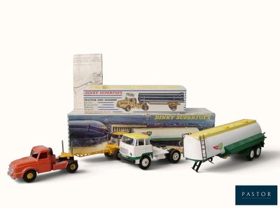 trois camions miniatures placés les uns à côté des autres sur une surface blanche