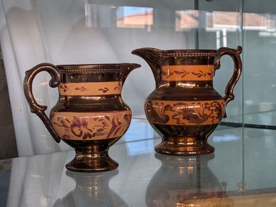 two vases sitting on a glass table in front of a window