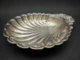 une assiette en argent ornée d'un grand motif en forme de coquillage