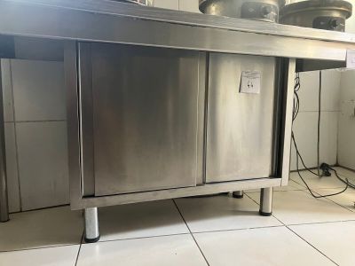 une table en acier inoxydable sur laquelle sont posés des casseroles et des poêles