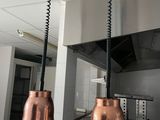 two copper bells hanging from the ceiling in the kitchen