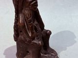 a small statue of a man sitting on a tree stump