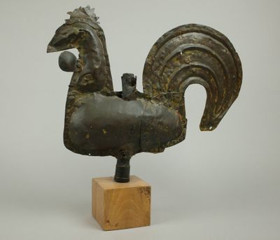 statue d'un coq posée sur un socle en bois, sur fond blanc