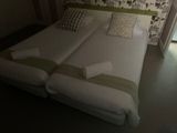 deux lits jumeaux dans une petite chambre dont l'un des murs est tapissé