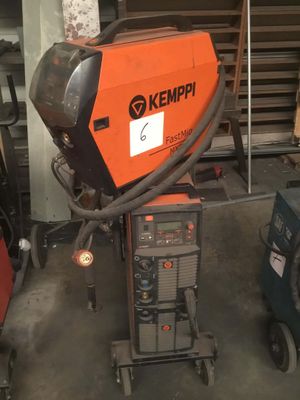 une soudeuse orange et noire dans un garage, à côté d'autres équipements