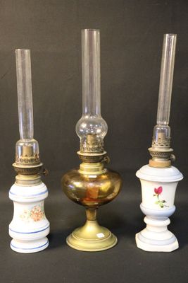 three antique oil lamps are lined up against a black background
