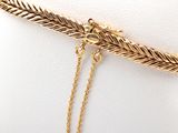 gold plated chain bracelet with a leaf charm on a white background