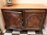 une armoire en bois à deux portes, sur laquelle est posé un vase