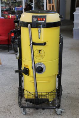 un dépoussiéreur jaune posé sur un chariot dans un magasin