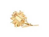 a close up of a gold brooch with leaves on a white background