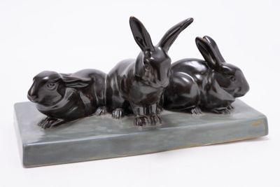 sculpture of three rabbits sitting on a marble base