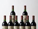 six bottles of red wine lined up on a wooden table