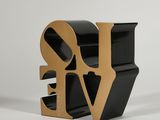 a close up of a black and gold love sculpture on a white background