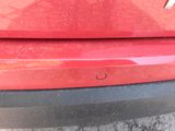 a close up of a red car ' s bumper with a hole in it