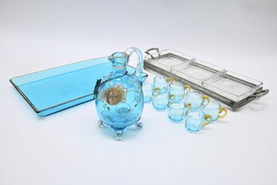 un vase en verre bleu et un plateau en argent posés sur une table blanche