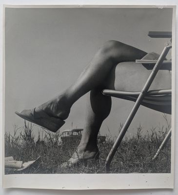 photographie en noir et blanc d'une femme assise sur une chaise, les jambes croisées