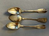 three silver spoons sitting on top of a table next to each other