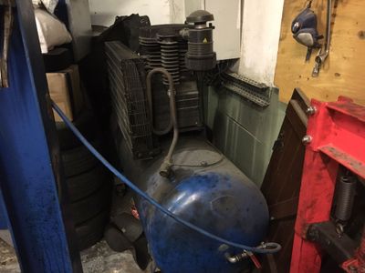 un compresseur bleu posé à côté d'un réservoir bleu dans un garage