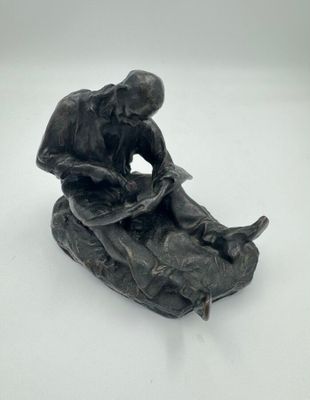 statue représentant un homme assis sur un rocher avec un chien